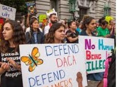 Lots of young kids holding signs outside at a demonstration that say Defend DACA Defend Dreamers and No Human Being is Illegal