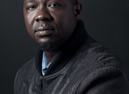 Middle aged black man, bald, in grey sweater, looking at the camera like he's a bit sad and a bit let down