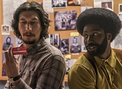 Young white man with dark hair and goatee sitting next to young black man with big afro and beard