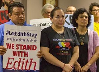 Latino people posing for camera looking grim, one man holding a sign that says #LetEdithStay We Stand with Edith