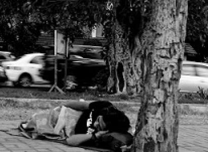 Black and white photo of person lying on the ground under a tree