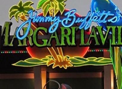 Neon sign with a parrot, palm trees, and the words in script Jimmy Buffet and the word in large capitals Margaritaville