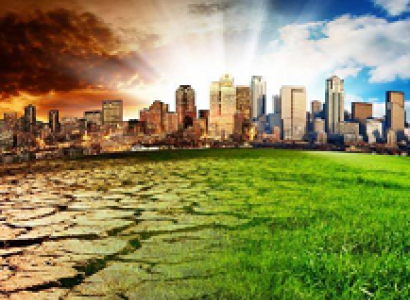 A cityscape against a horizon with sunrays shooting from the ground to a blue sky on right and fiery sky on left with the fore ground at right green grass and at left cracked and dry