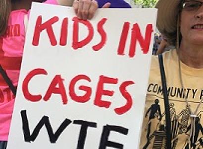 Woman holding sign saying Kids in Cages WTF GOP
