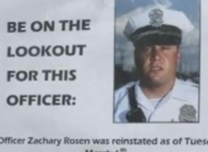 The photo of a white man in a big white police hate with black brim and badge on it scowling on his face and a cop uniform with the words a the left saying Be on the lookout for this officer
