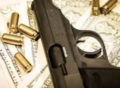 Dark gray handgun lying sideways on a table with gold bullets strewn around it