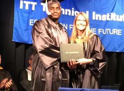 Black man in graduation robe and hat receiving diploma