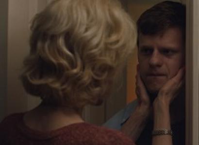 Back of wWoman with blonde buffant hairdo with both hands holding a young man's face