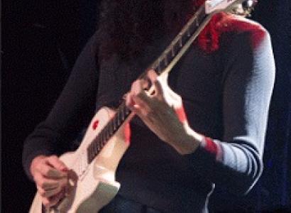 Guy playing guitar with Kentucky Fried chicken bucket on his head, he has white makeup like a mime