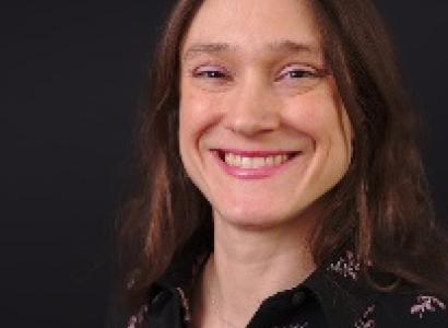 Youngish white woman with straight brown hair smiling at the camera
