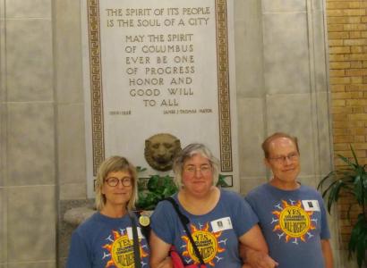 Three people standing in front of etched sign on wall