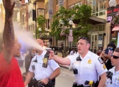 Cop spraying black man with hands in air