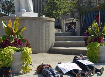 Student lying on ground beneath Columbus statue