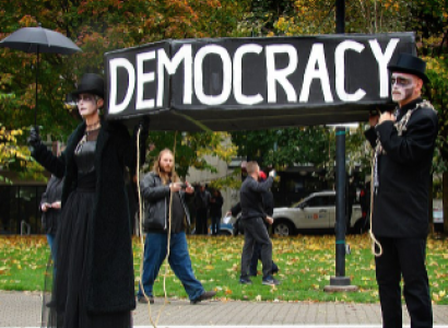 People in a funeral procession holding a democracy sign