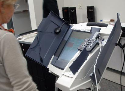 Older woman standing by an electronic voting machine