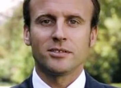 Young looking man with brown hair receding hairline against trees in background