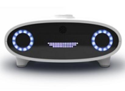 Black faced white bordered device like a radio with two round knobs facing out that look like eyes and lines in the middle that look like a mouth