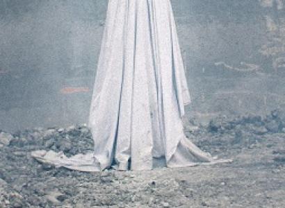 Person in a white sheet with two eye holes against an eerie gray background