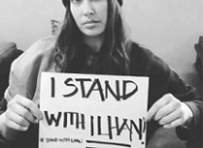 Black and white photo of woman holding small sign saying I Stand with Ilhan