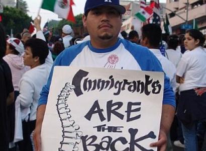 Man holding sign saying Immigrants are the Backbone of this country