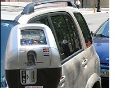 Close up of a parking meter and cars parked behind it