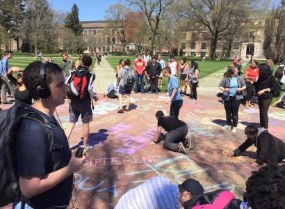 Students coloring with chalk on the Oval to cover up hate speech