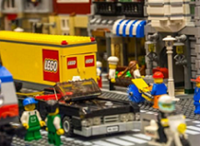 Storefronts made from legos and Lego word on side of truck and little lego people 