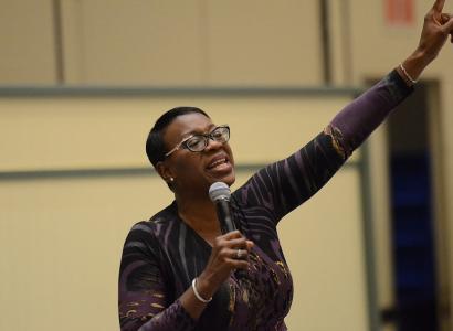 Black woman giving a speech raising her arm in the air