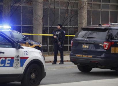 Police car and officer with gun outside building with crime tape around it