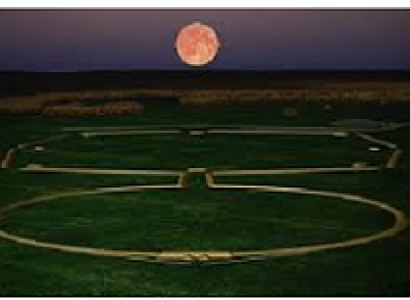 Green ground and dusky sky with huge red moon and a design on the ground