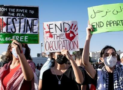 From left to right, protest signs read: "From the river to the sea Palestine will be free", "End the occupation", "End apartheid."