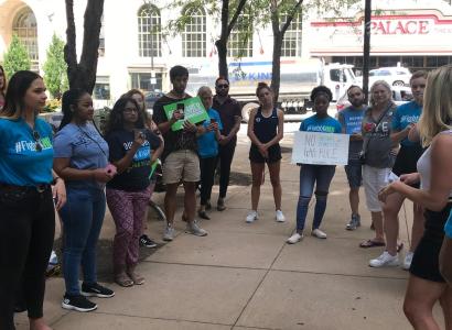 Students standing outside holding signs on a city street