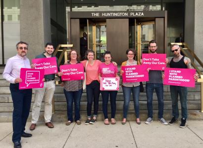 People with pink signs standing outside a government building