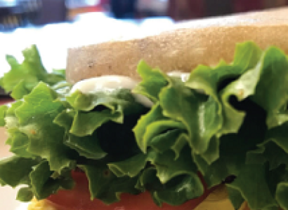 Close up of a sandwich with lettuce and tomato spilling out the side