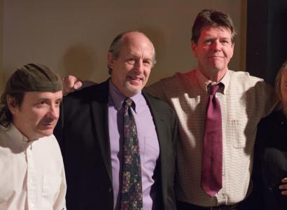 Four middle aged white guys, some in suits, standing together with their arms around each other