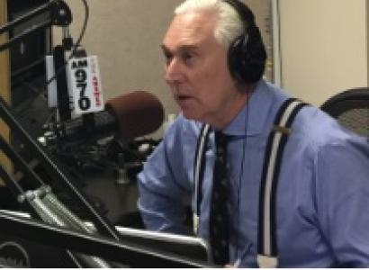 Gray haired white man in blue shirt wearing headphones talking into an elaborate microphone set up