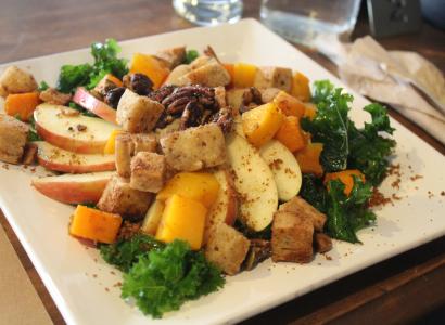 A square white plate filled with vegetables and green garnishes