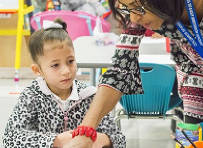 Teacher leaning over showing something to small child
