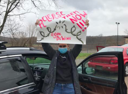 Woman holding a sign saying Release Them Now