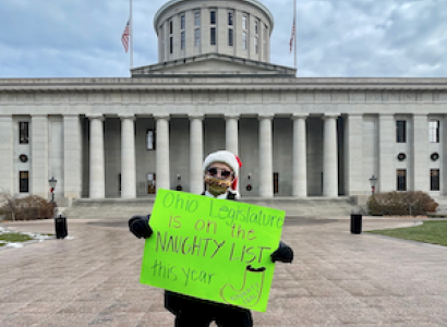 Man holding sign in front of Statehouse