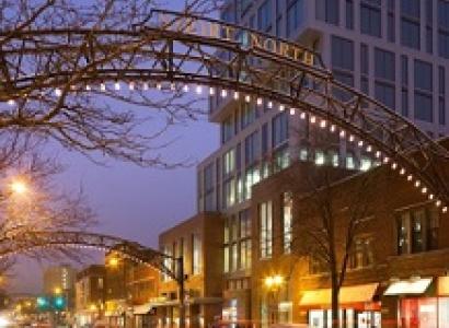 Lighted metal arch over street next to tall building