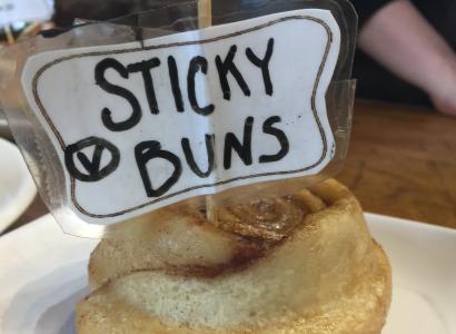 A cinnamon bun with a sign on it saying Sticky Buns