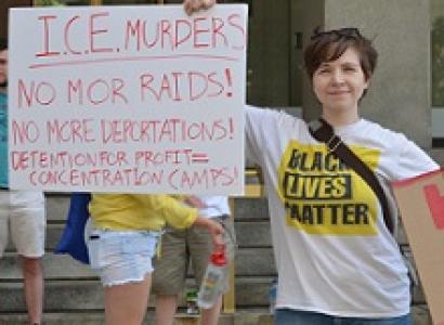 White woman in Black Lives Matter Tshirt holding a sign that says ICE murders
