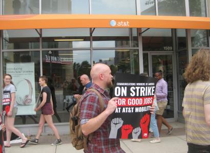 Guy in a strike protest holding a sign that says On Strike