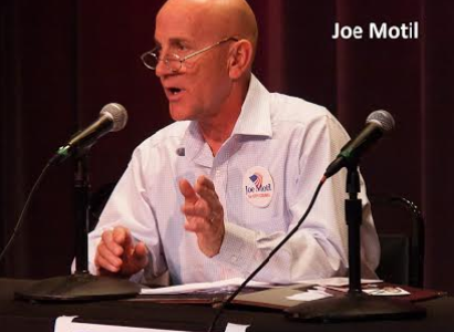 White bald man in white shirt at a podium speaking