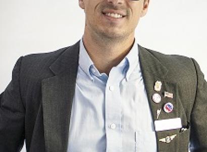 Travis Irvine in a suit and glasses