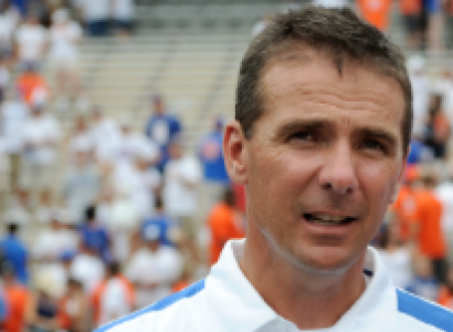White guy in a white shirt with football stadium seats behind him