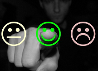 A black and white man in the background pointing his finger to the camera with a straight line face, happy face and sad face drawn on front