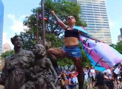 Woman posing on statue wearing trans flag