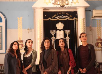 Four women staring up at something above them, standing in front of an elaborately decorated doorway